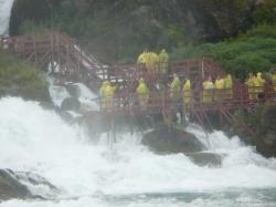 Tourists in yellow raincoats on stairs next to Bridal Veil Falls as viewed from Maid of the Mist.jpg